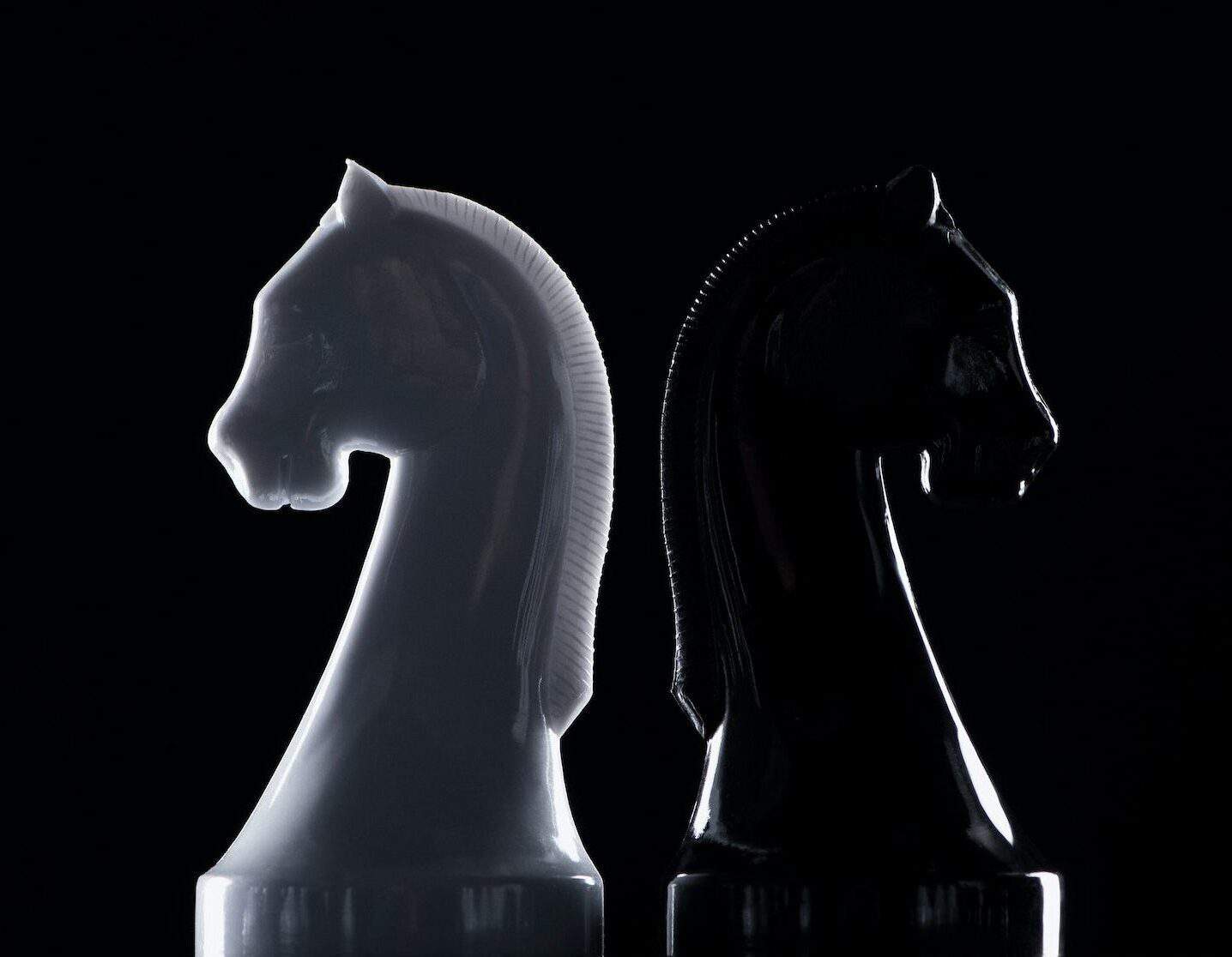 Silhouettes Of White And Black Chess Knights Isolated On Black Business Concept E1687039337724