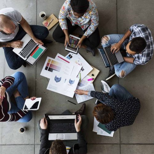 Group of people brainstorming and collaborating on the floor, symbolizing Business Process Management (BPM) and efficient Business Process Outsourcing Services.